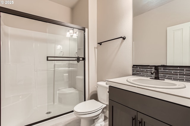 bathroom with vanity, backsplash, a shower with shower door, and toilet