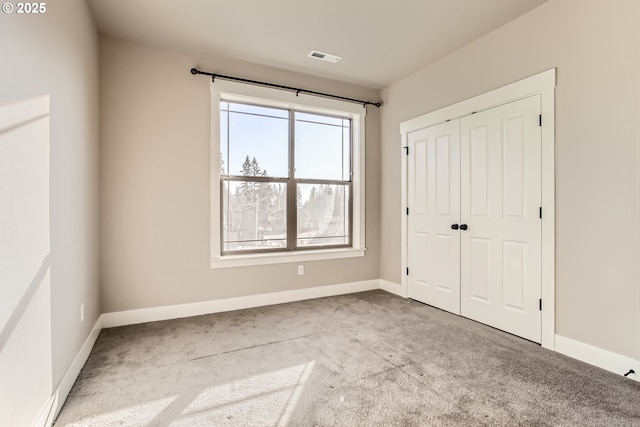 unfurnished bedroom featuring light colored carpet and a closet