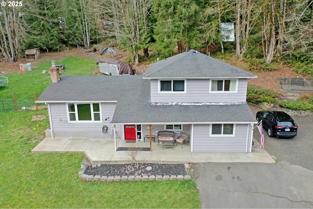 tri-level home featuring aphalt driveway, a front yard, and a patio