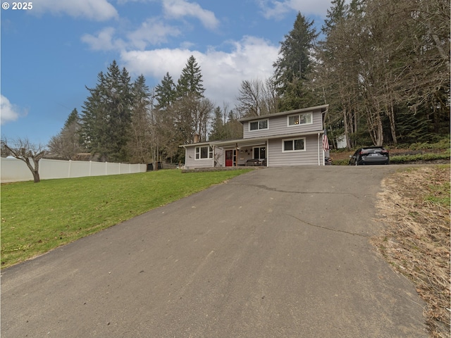 view of front of property featuring aphalt driveway, a front yard, and fence