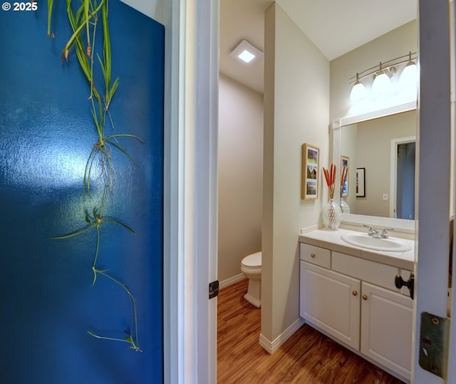 bathroom with toilet, hardwood / wood-style floors, and vanity