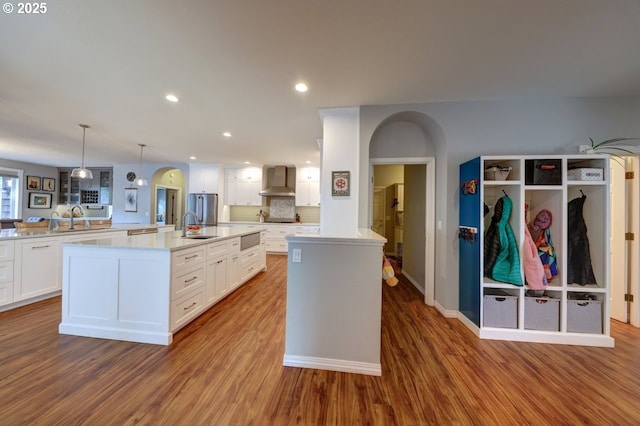 kitchen featuring decorative light fixtures, backsplash, wall chimney exhaust hood, and a spacious island