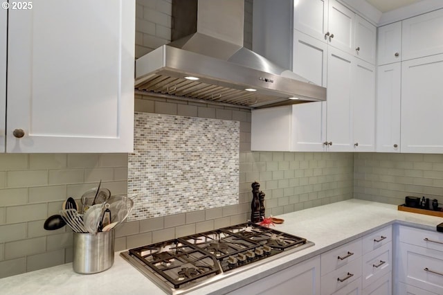 kitchen with white cabinetry, stainless steel gas cooktop, backsplash, and wall chimney range hood