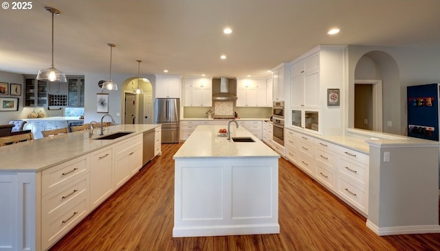 kitchen featuring pendant lighting, wall chimney exhaust hood, sink, backsplash, and a large island