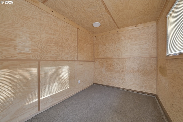 unfurnished room featuring carpet flooring, wooden ceiling, and wood walls