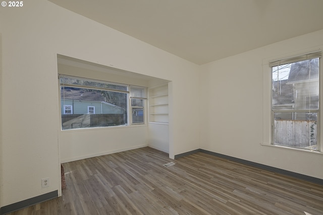 spare room featuring dark wood-type flooring and built in features