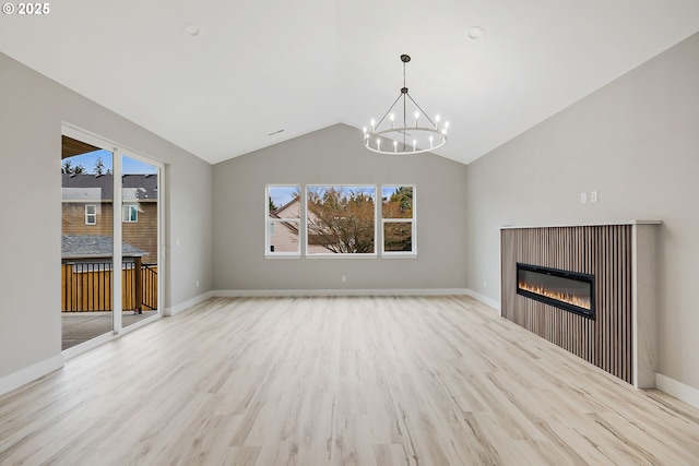 5477 SE Golden Rd, Hillsboro, OR 97123 - unfurnished living room featuring a chandelier, plenty of natural light, a glass covered fireplace, wood finished floors, and high vaulted ceiling