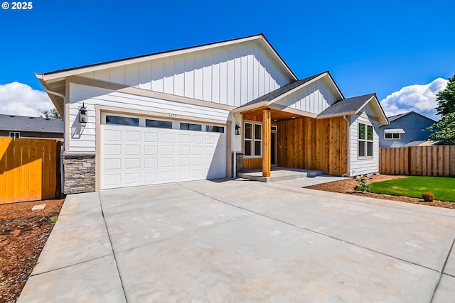 5477 SE Golden Rd, Hillsboro, OR 97123 - view of front of home with board and batten siding, an attached garage, concrete driveway, and stone siding