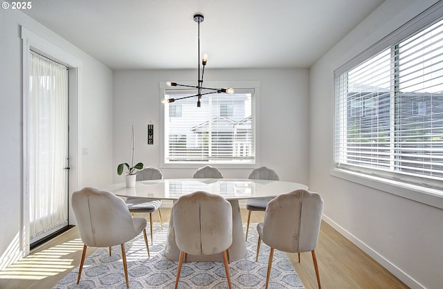 dining room with baseboards, light wood-style floors, and a notable chandelier