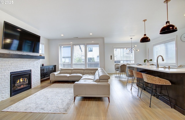 living room with light wood-style flooring, a stone fireplace, a wealth of natural light, and recessed lighting