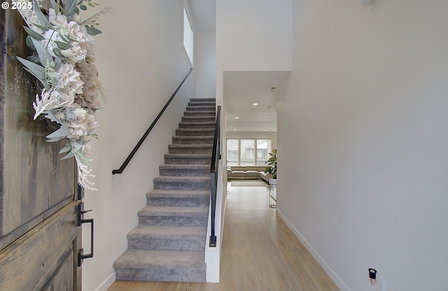 foyer entrance featuring stairs, light wood-style floors, a towering ceiling, baseboards, and recessed lighting