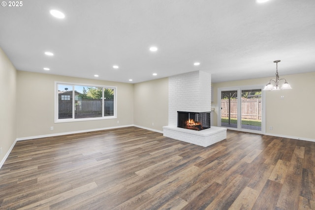 1080 Lockhaven Dr, Keizer, OR 97303 - unfurnished living room with a brick fireplace, dark wood-type flooring, baseboards, recessed lighting, and a chandelier