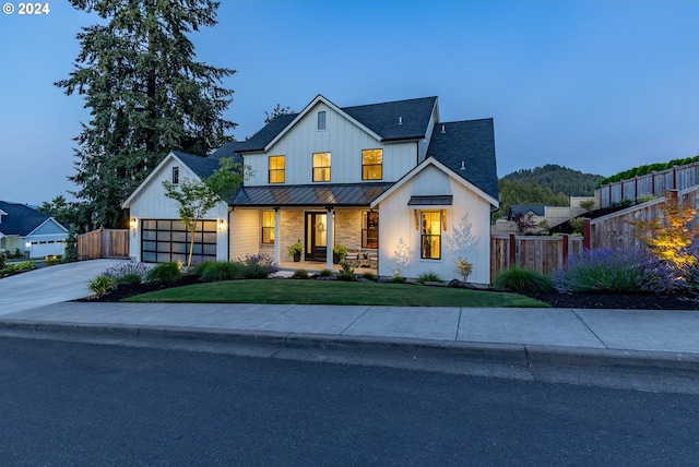 modern farmhouse style home with covered porch, a garage, and a lawn