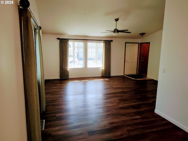 empty room with dark wood-style floors, visible vents, baseboards, and a ceiling fan