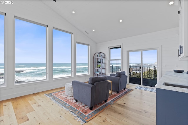 living room with plenty of natural light, lofted ceiling, and light wood-style floors