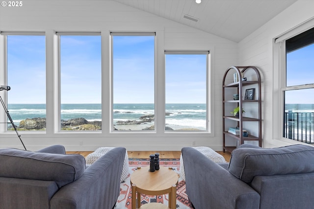 living room with vaulted ceiling, a wealth of natural light, visible vents, and wood finished floors