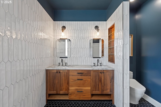 bathroom with toilet, tile patterned floors, double vanity, and a sink