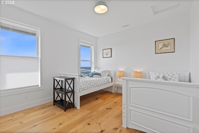 bedroom featuring attic access, baseboards, visible vents, and light wood-style floors