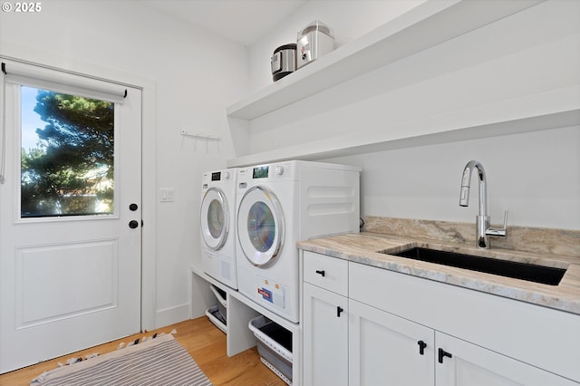 laundry room featuring washer and clothes dryer, cabinet space, a sink, and light wood-type flooring