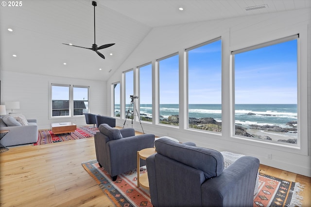 living area with wood finished floors, high vaulted ceiling, visible vents, ceiling fan, and a water view