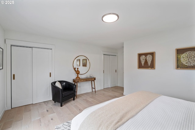 bedroom with two closets and light hardwood / wood-style flooring