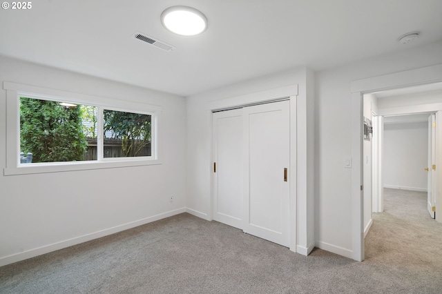 unfurnished bedroom with light colored carpet and a closet