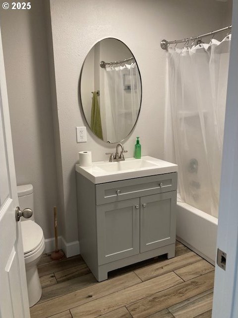 100 NW 7th Ave, John Day, OR 97845 - full bathroom featuring vanity, wood finished floors, toilet, and shower / bath combo with shower curtain