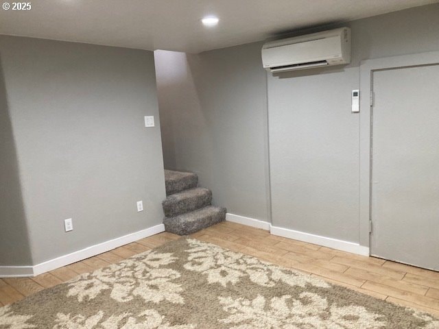 100 NW 7th Ave, John Day, OR 97845 - finished basement featuring a wall unit AC, wood finished floors, baseboards, recessed lighting, and stairs