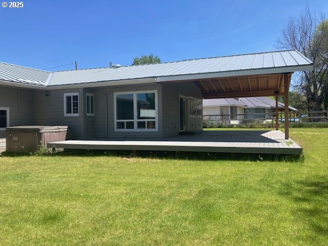 100 NW 7th Ave, John Day, OR 97845 - rear view of house featuring a lawn, metal roof, a deck, and a hot tub