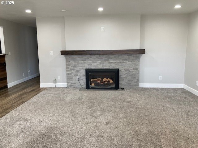 100 NW 7th Ave, John Day, OR 97845 - unfurnished living room with baseboards, carpet flooring, recessed lighting, a fireplace with flush hearth, and wood finished floors