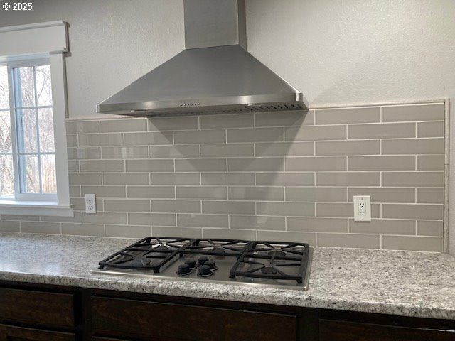100 NW 7th Ave, John Day, OR 97845 - kitchen view of wall chimney range hood, stainless steel gas stovetop, decorative backsplash, and dark brown cabinets