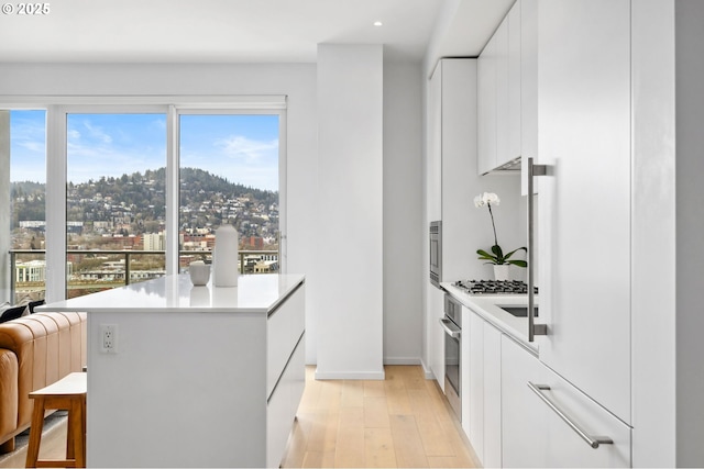 kitchen featuring stainless steel appliances, modern cabinets, white cabinetry, and light countertops