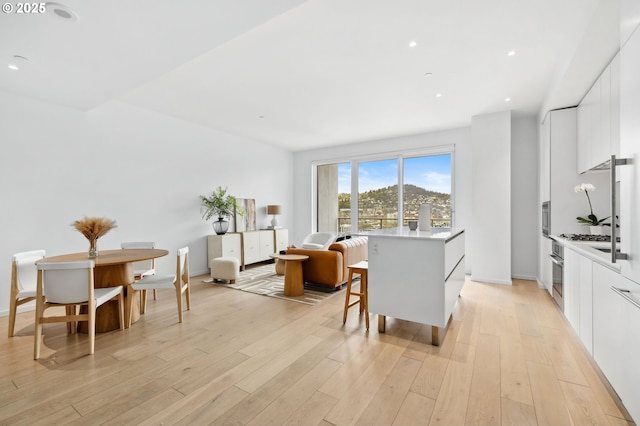 kitchen featuring light wood-style flooring, a kitchen island, white cabinets, and light countertops