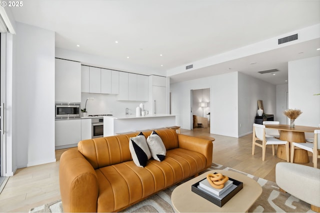 living area featuring light wood-type flooring, visible vents, and recessed lighting