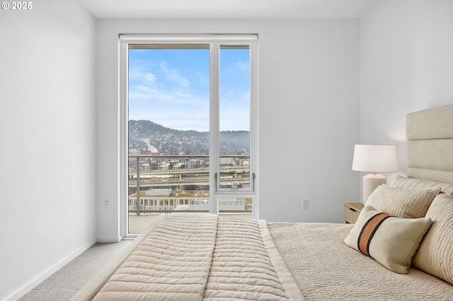 carpeted bedroom featuring access to outside, multiple windows, a mountain view, and baseboards