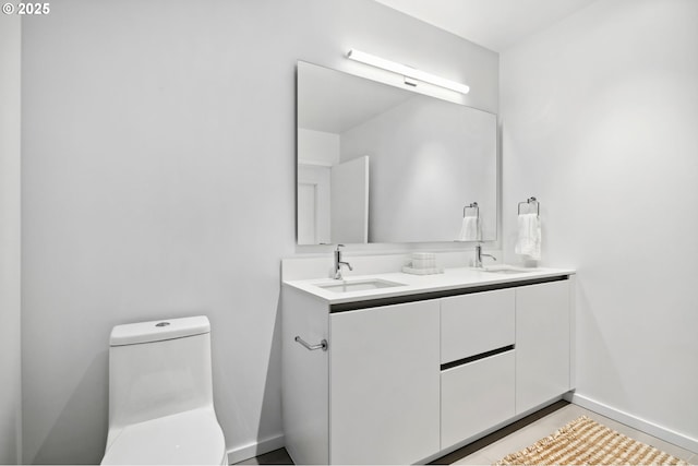 full bath featuring baseboards, a sink, toilet, and double vanity