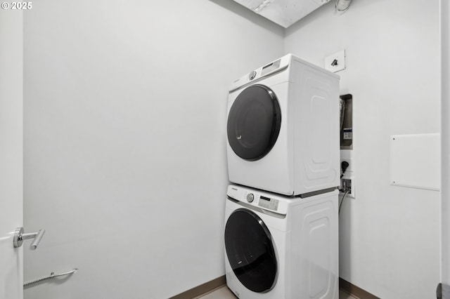 laundry area with laundry area, stacked washer and clothes dryer, and baseboards