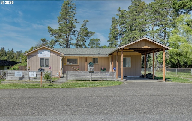 view of front of house featuring fence, a carport, and a shingled roof