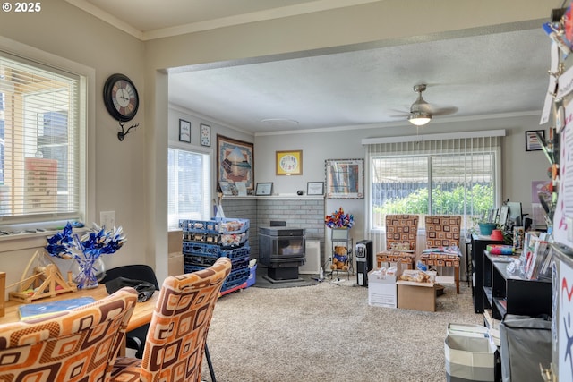 carpeted home office with ornamental molding, a wood stove, and a healthy amount of sunlight