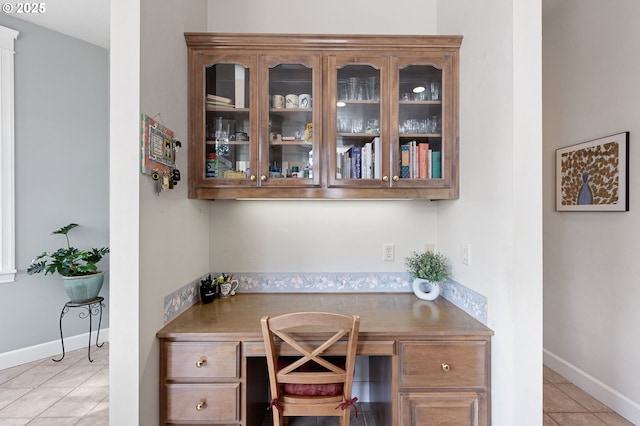 home office with light tile patterned flooring, built in desk, and baseboards