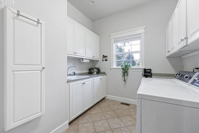 clothes washing area featuring visible vents, a sink, washer and dryer, cabinet space, and baseboards