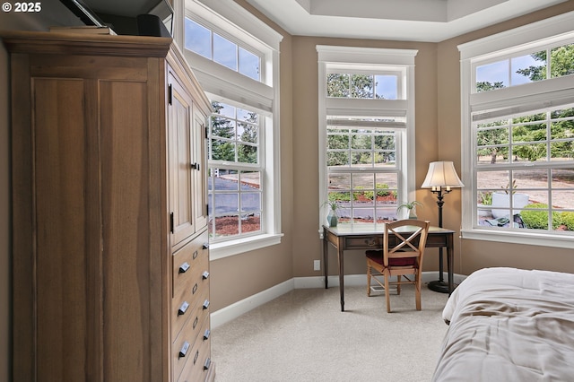 bedroom with multiple windows, light carpet, baseboards, and an office area