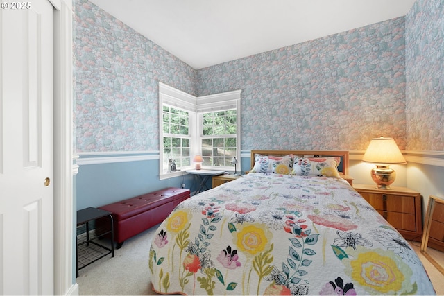 bedroom featuring wallpapered walls, wainscoting, and light colored carpet