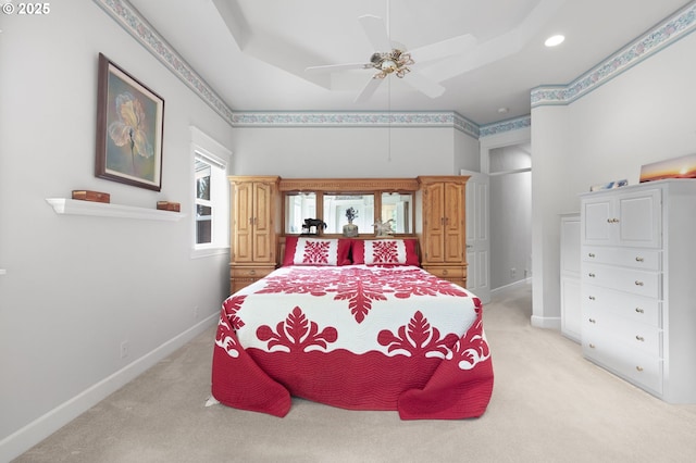 bedroom featuring light carpet, a ceiling fan, a raised ceiling, and baseboards