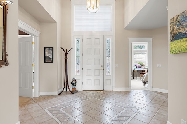 foyer featuring a towering ceiling, baseboards, and light tile patterned floors