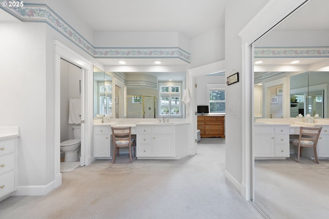full bath with a shower stall, baseboards, toilet, and two vanities