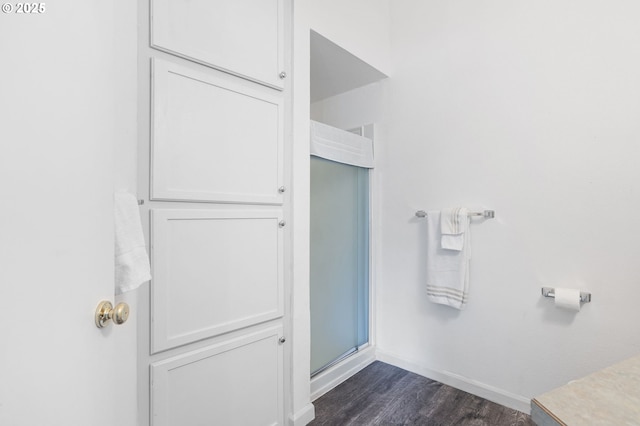 bathroom featuring wood finished floors, an enclosed shower, and baseboards