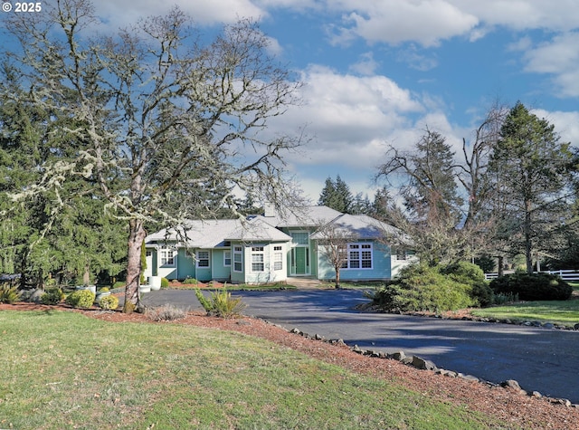 ranch-style home featuring aphalt driveway and a front lawn