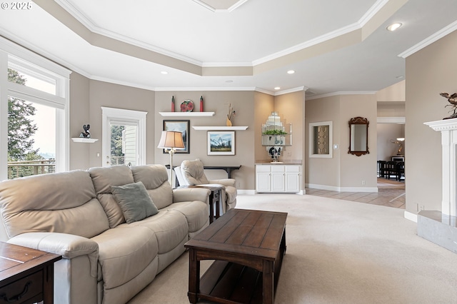 living room featuring a raised ceiling, light colored carpet, recessed lighting, ornamental molding, and baseboards