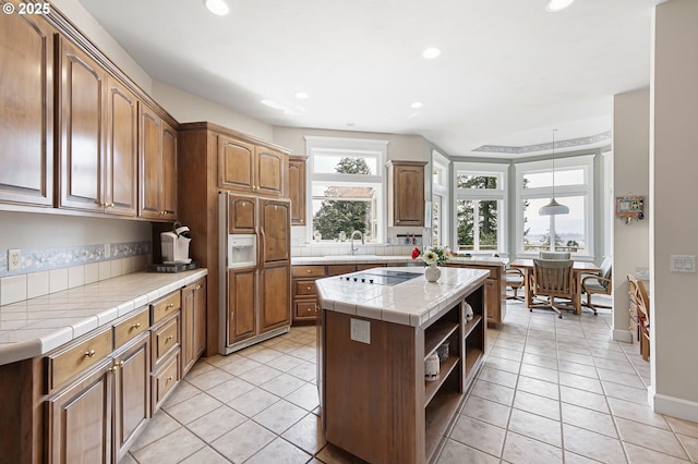 kitchen featuring tile countertops, open shelves, a center island, paneled refrigerator, and recessed lighting